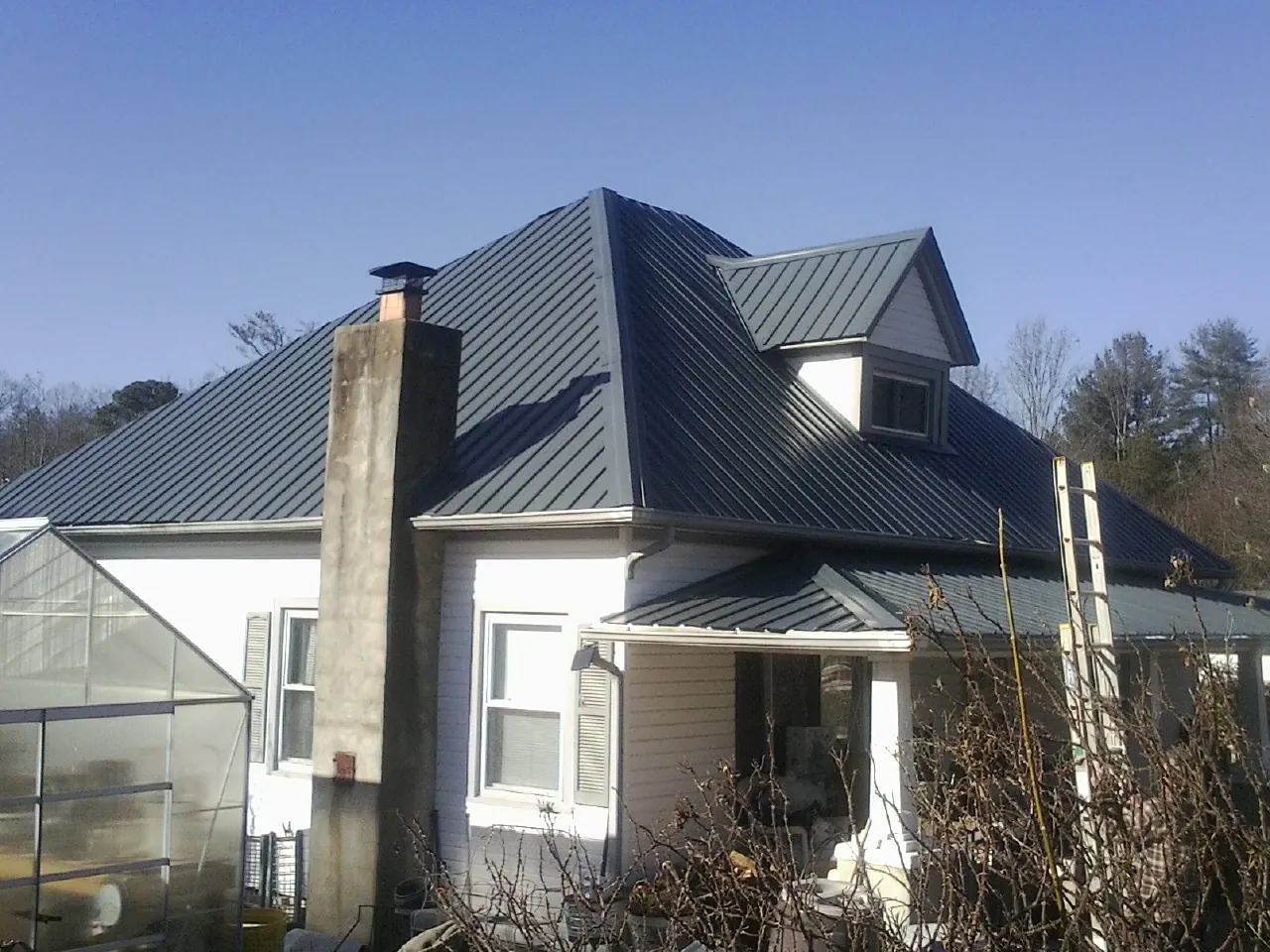 Dark blue standing seam metal roof on a white farmhouse with dormer — Slate & Tile Roof Repair by Roofing Brothers in Fredonia