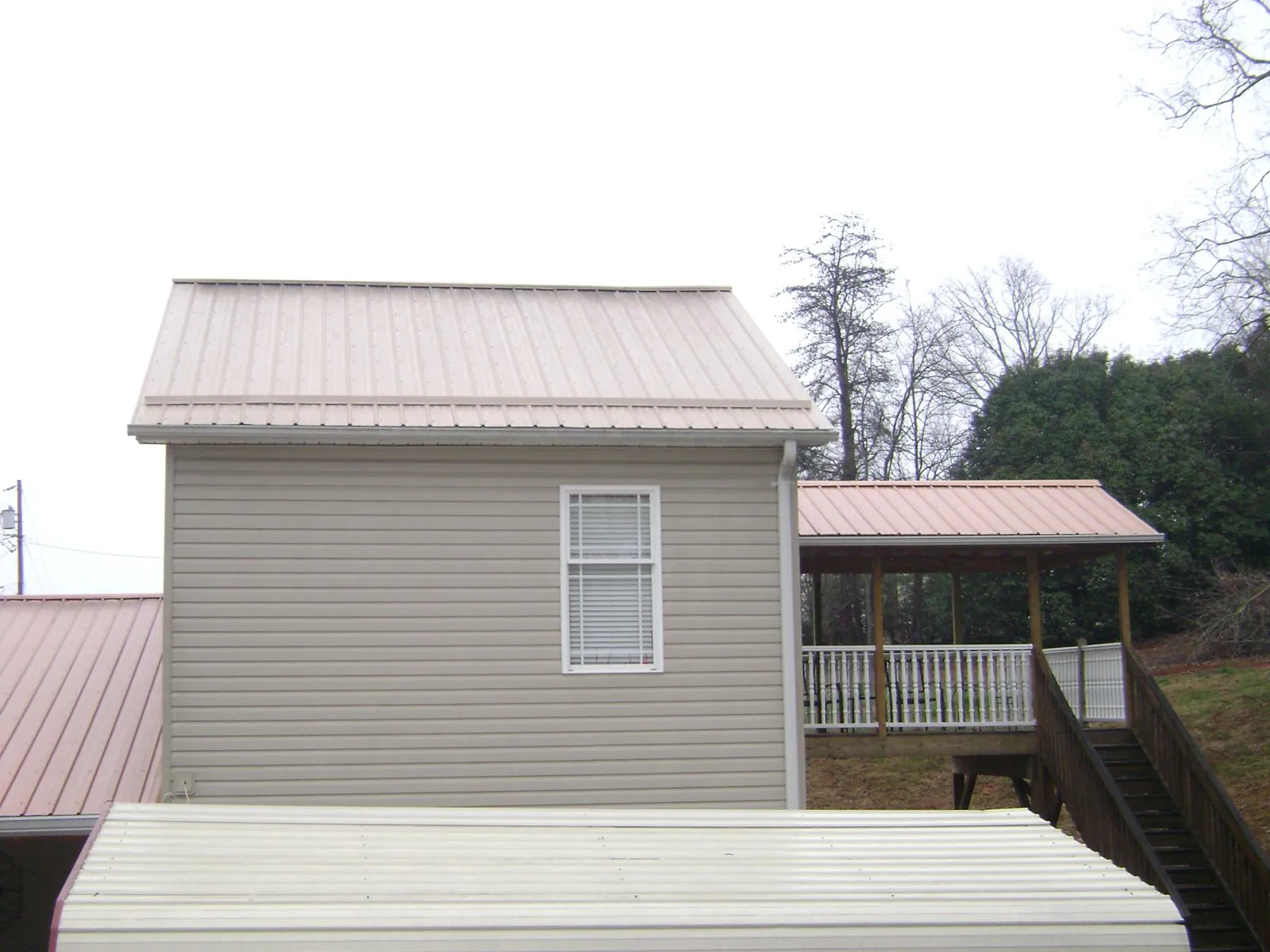 Tan metal roofs on a two story addition and attached porch, from a Roof Replacement job in Fredonia